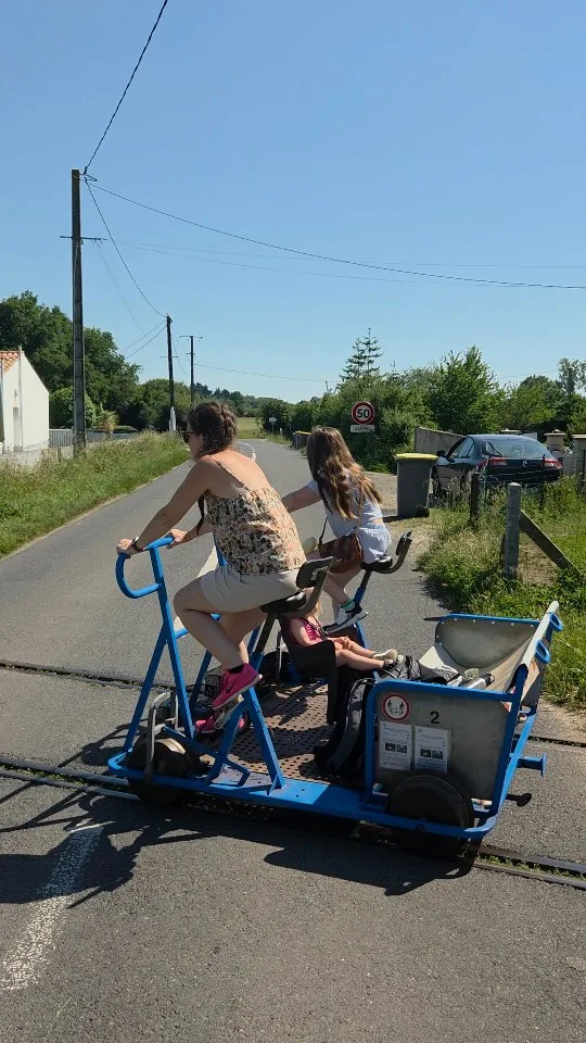 Deux personnes pédalant sur le vélo-rail de Commequiers, au milieu de la campagne